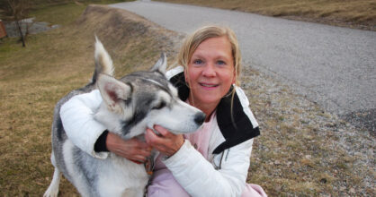 Nainen on kyykistyneenä koiran vieressä.