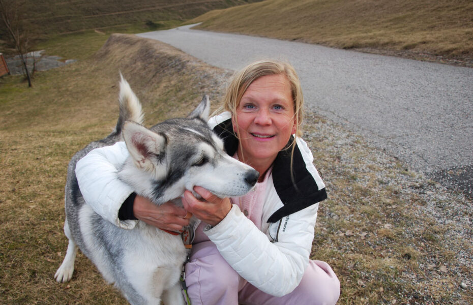 Nainen on kyykistyneenä koiran vieressä.