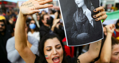 Mielenosoittajien joukko. Nainen pitää kädessää kuvaa Masha Aminista.