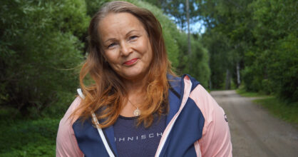 Mette-Maarit seisoo kadulla verkkatakissa.