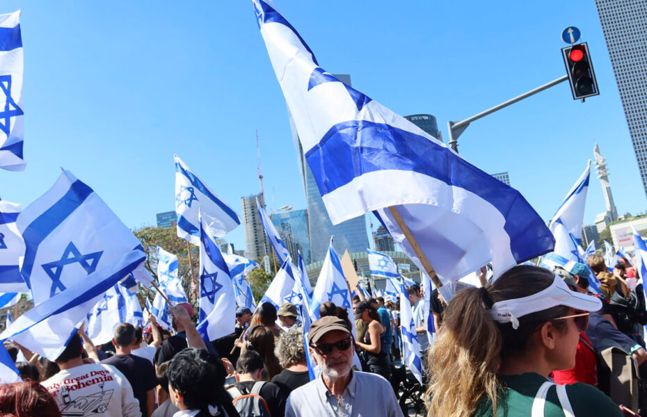 Joukko ihmisiä, jotka pitävät käsissään Israelin lippuja.