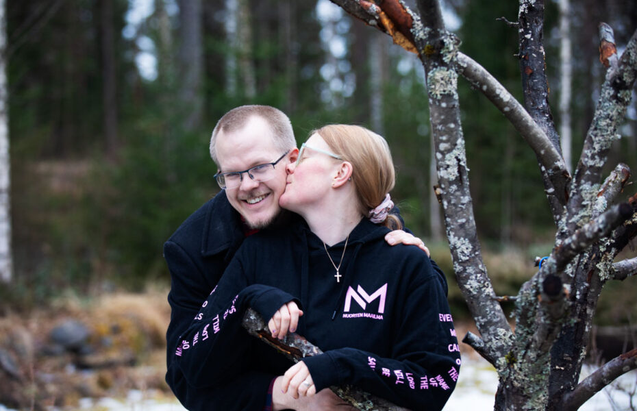 Nainen antaa suukon miehen poskelle.