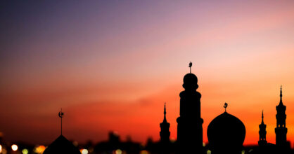 Kaupunki pimenevässä illalla. Torneissa näkyy islamin symboli puolikuu.