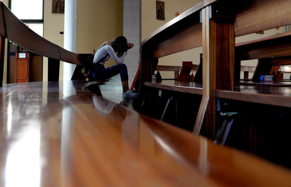 Nainen rukoilee kirkon penkissä.