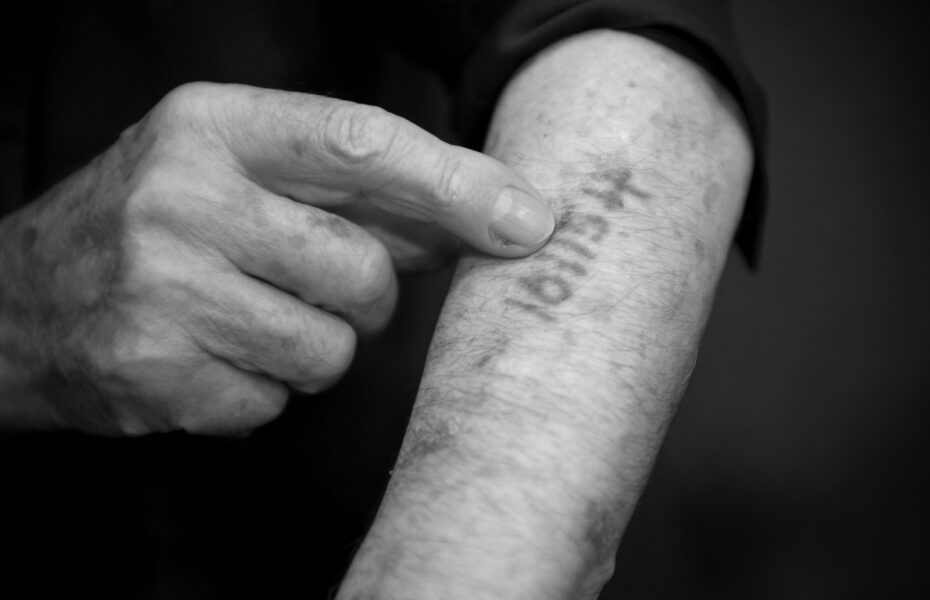 Mustavalkoinen kuva miehen käsivarresta, jossa on numerosarja.