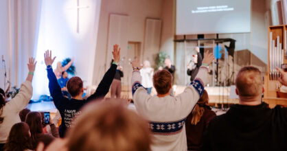 Nuoret ylistävät kädet kohotettuina kohti kattoa.