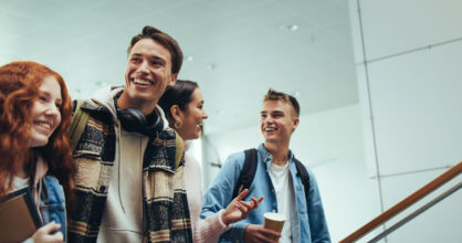 Nuoret opiskelijat kävelevät portaissa ja hymyilevät.