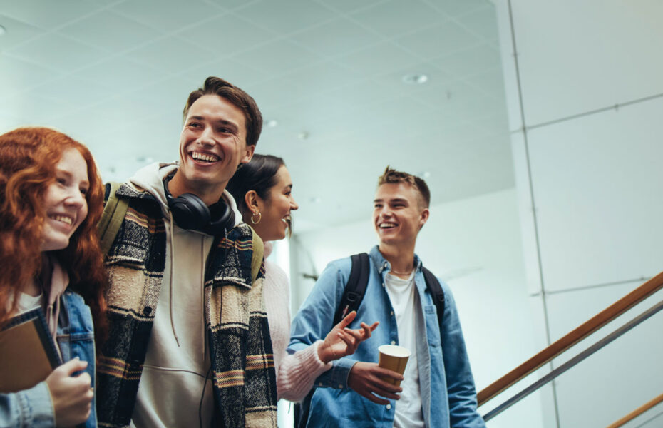 Nuoret opiskelijat kävelevät portaissa ja hymyilevät.