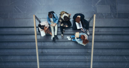 Viisi nuorta istuu portailla opiskelemassa. Kuva otettu ylhäältä päin.