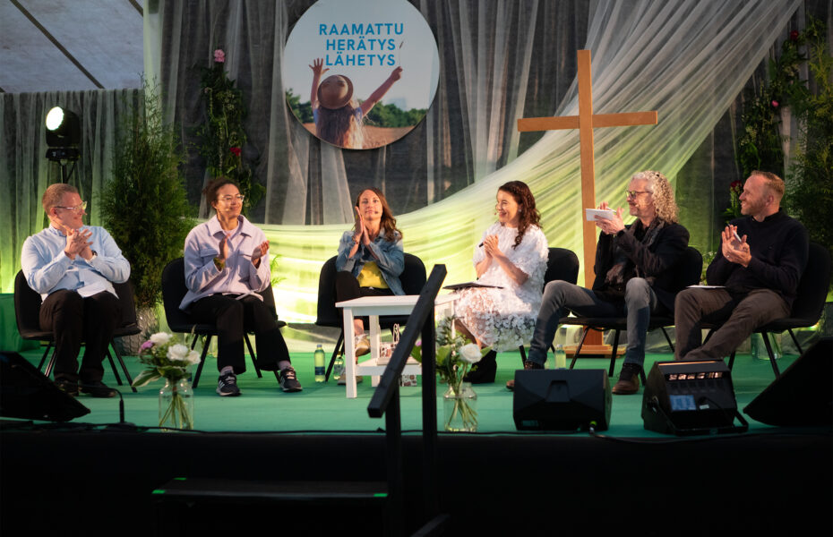 Kuusi henkilöä taputtaa lavalla.