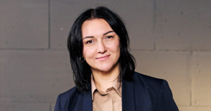 Olena hymyilee. Hänellä on tummat hiukset, jotka yltävät hartioille saakka.