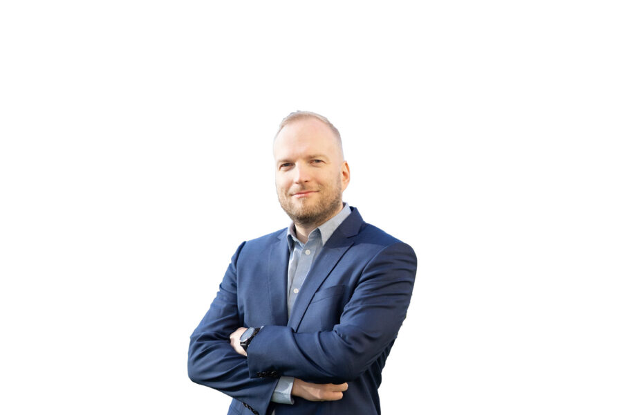 Santeri Marjokorpi hymyilee. Hänellä on paita ja puvun takki.