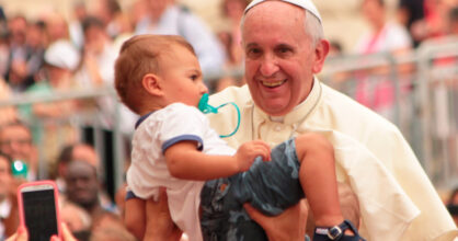 Väkijoukossa kädet nostavat pienen lapsen paavin eteen.