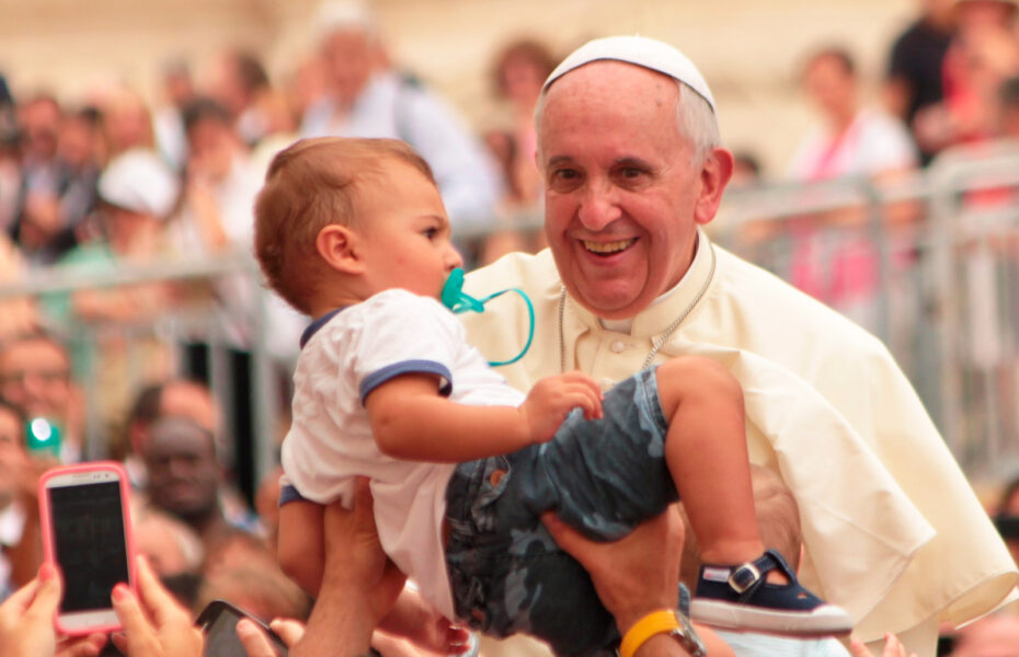 Väkijoukossa kädet nostavat pienen lapsen paavin eteen.