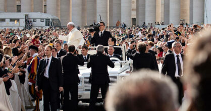 Paavi Franciscus tervehtii ihmisiä autostaan. Häntä ympäröivät turvamiehet.