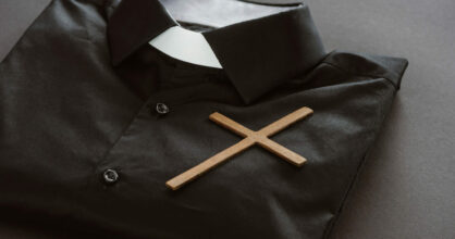 Viikattu papin paita, jonka päällä on puinen risti.