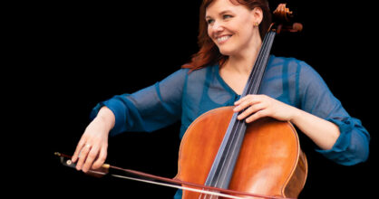 Kuvassa Pauliina Haustein soittaa selloa ja hymyilee.