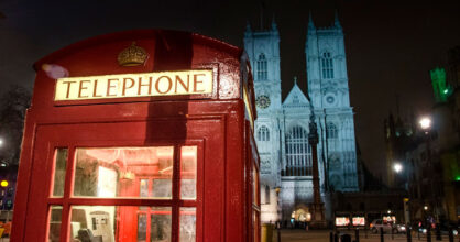 Punainen puhelinkoppi, jonka takana on kirkko.