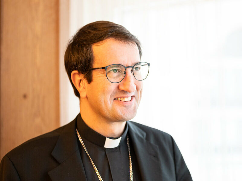 Raimo Goyarrola hymyilee. Hänellä on silmälasit ja papinpaita.