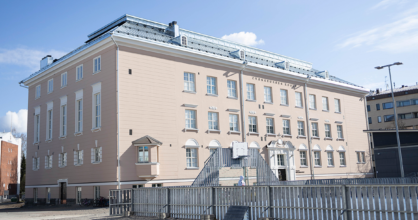 Iso kolmikerroksinen koulurakennus. Vieressä koripallokenttä.