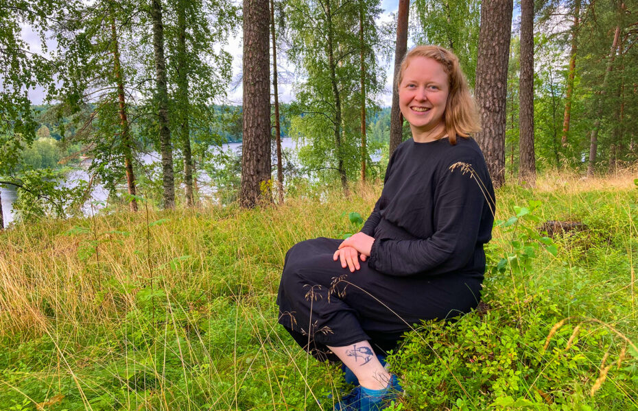 Nainen istuu metsässä ja nauraa.
