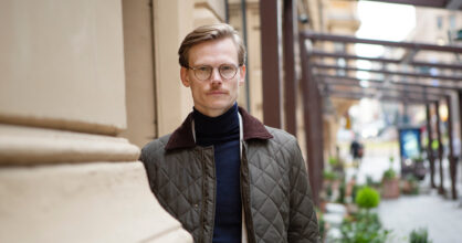 Mies seisoo kaupungin kadulla silmälaseissa takki päällä.