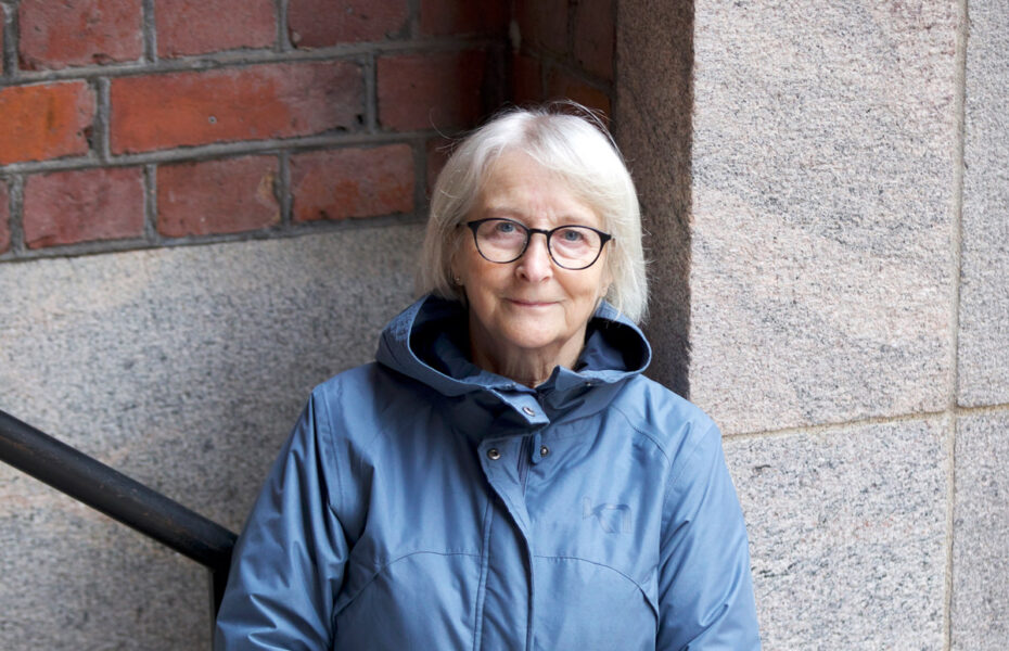 Sirkka-Liisa Huhtisella on silmälasit ja harmaa polkkatukka sekä sininen takki.