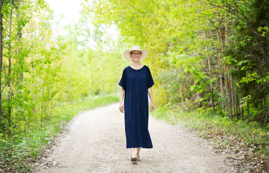 Sofia Ziessler-Korppi kävelee hiekkatietä pitkin. On kesä, ja hänellä on pitkä mekko ja hattu.