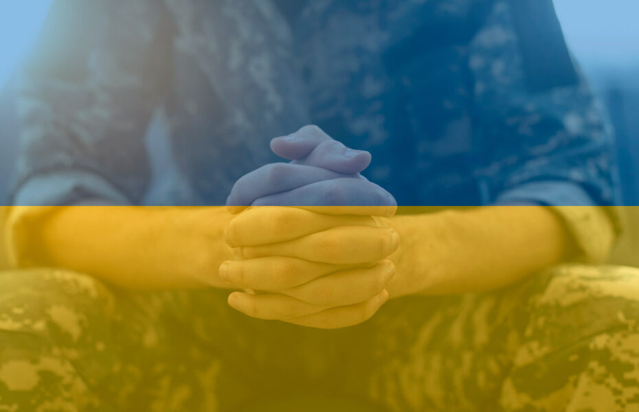 Sotilas rukoilee. Kuvassa on Ukrainan lipun värit.