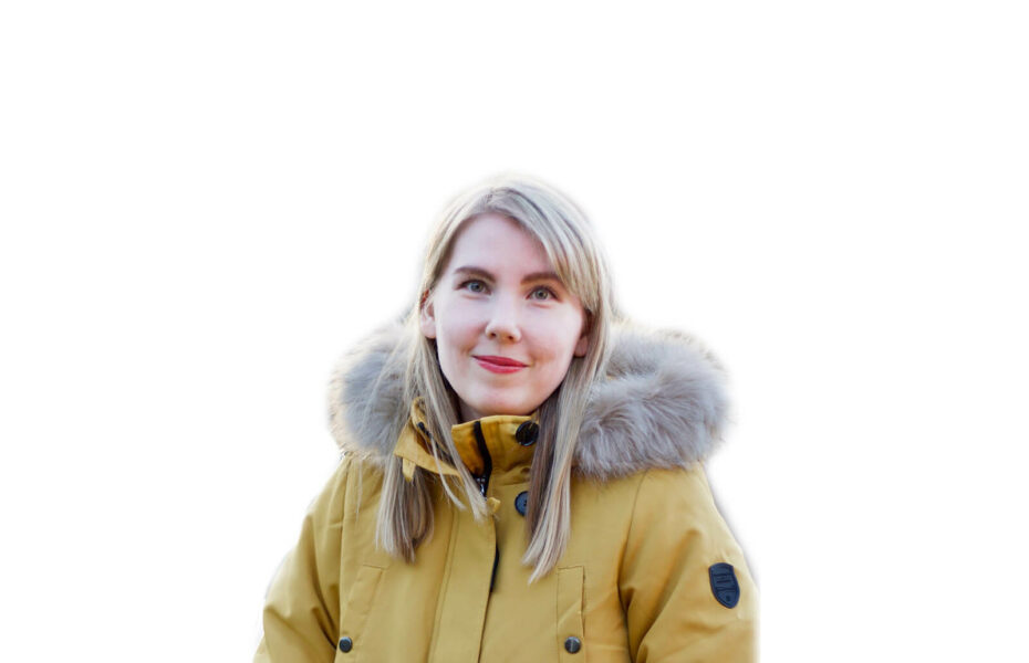Keltaiseen talvitakkiin pukeutunut Susanna Sarimaa katsoo kameraan. Tausta on valkoinen.