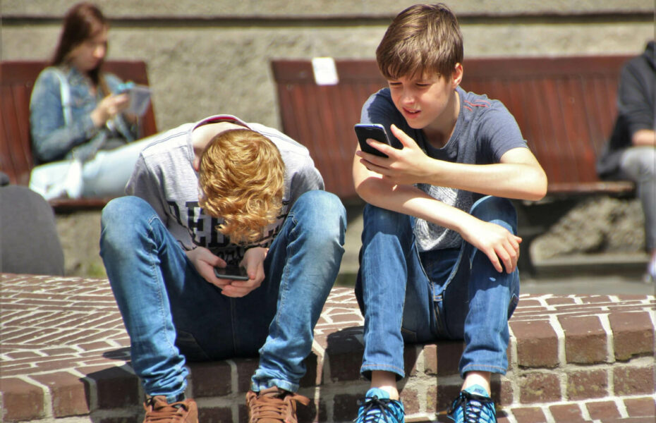 Teinipojat istuvat portailla ja selaavat puhelimia.