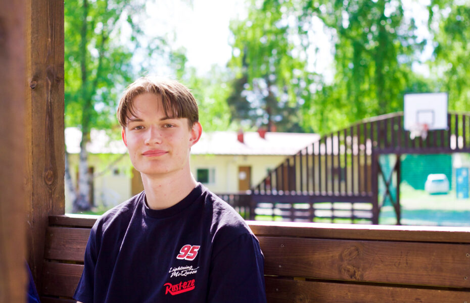Tomas istuu penkillä koulun pihalla.