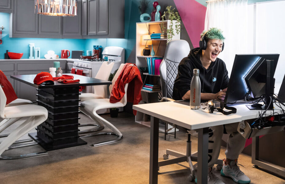 Mies istuu koneen äärellä. Hänellä on kuulokkeet. Taustalla näkyy hänen asuntonsa sisustusta ja huonekaluja.