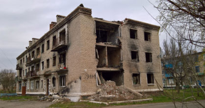 Pommitettu kolmikerroksinen talo. Osa seinästä on sortunut, ja tiiliseinä on hiiltynyt.