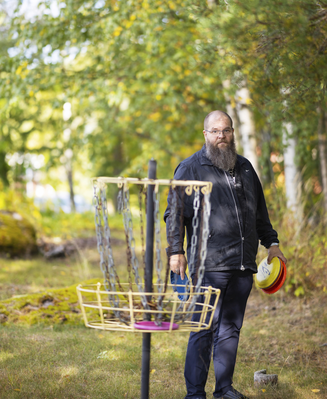 Mies seisoo frisbee-golf maalin takana frisbeet kädessä.