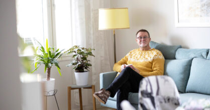 Veijo Grönholm istuu sohvalla olohuoneessa.