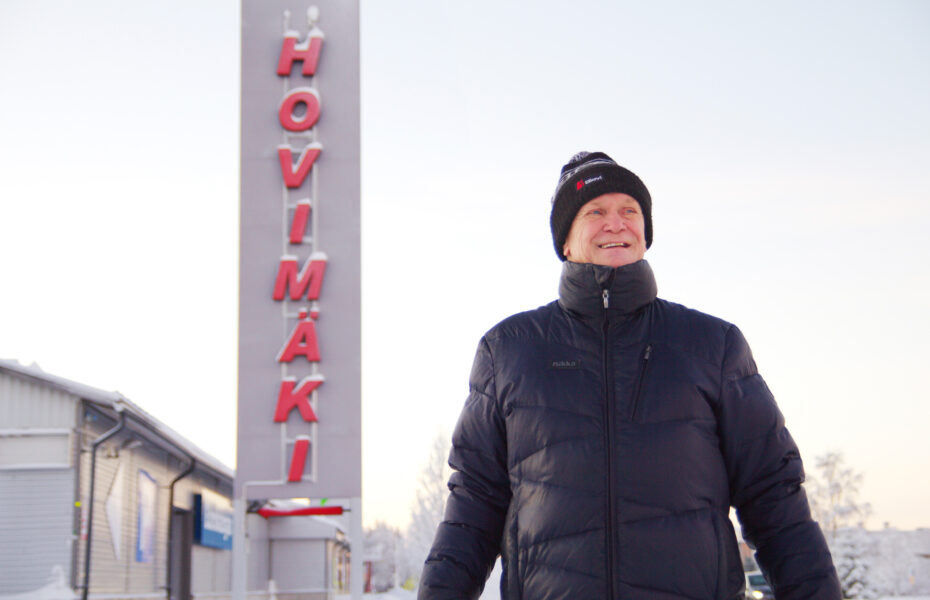 Mies pakkasessa. Taustalla kauppa jossa lukee "hovimäki".
