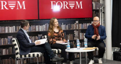 Kaksi miestä ja yksi nainen istuvat pöydän ääressä ja keskustelevat